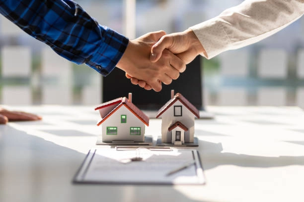 hands shaking with small house and paper on table -real estate consulting