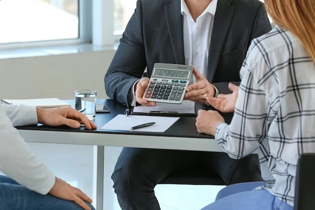 three people gather with calculator and paper having conversation -real estate consulting