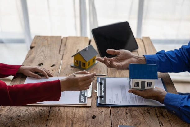 two people conversing talking about real estate, holding a blue house and a pen -real estate developers