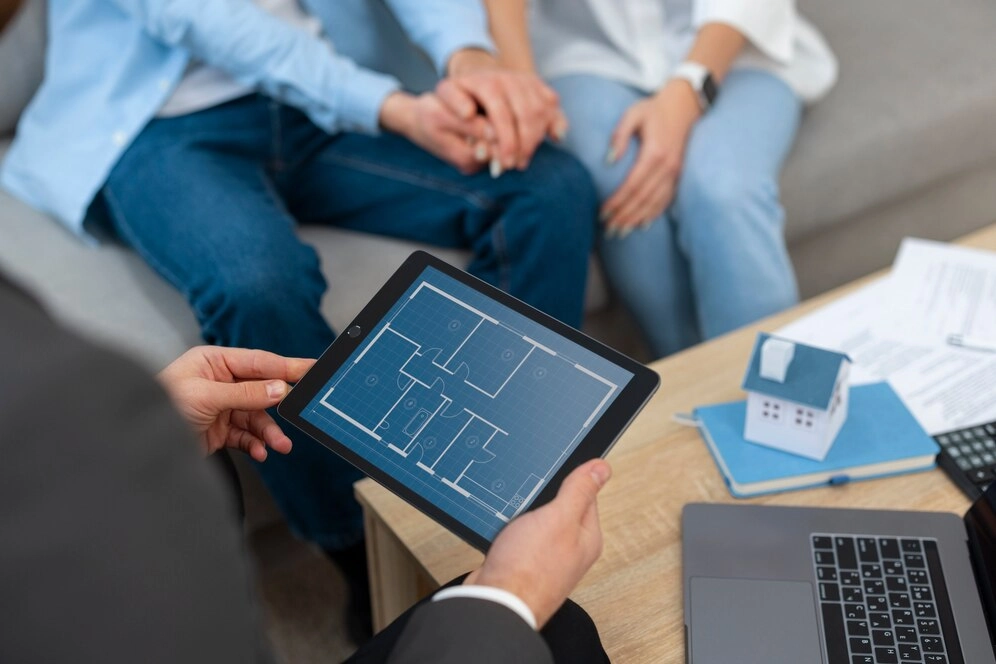 three people conversing about real estate, man holding a tablet with house plan -real estate developers