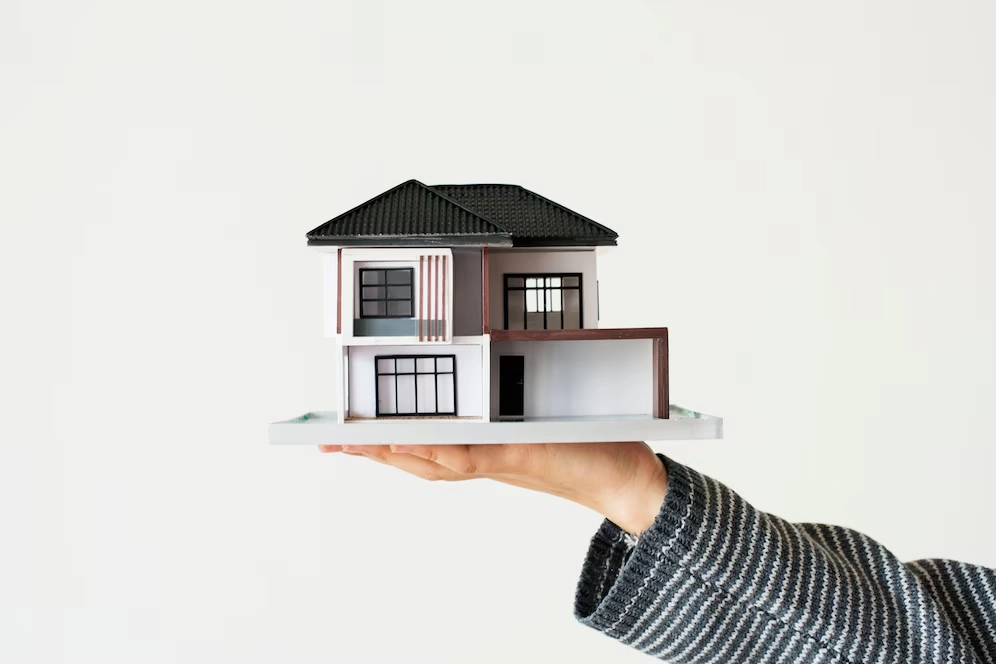 small miniature house on hand of person -real estate broker vs agent