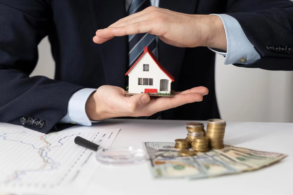 miniature house person holding with money on top of paper -real estate finance