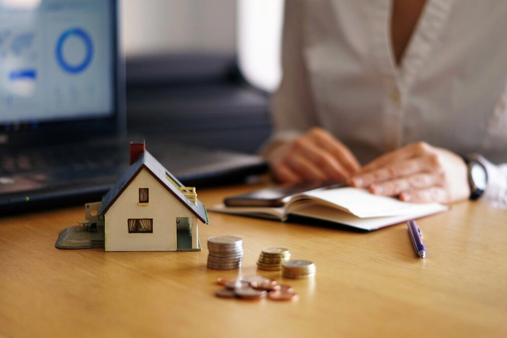 miniature house with coins front of person -real estate finance