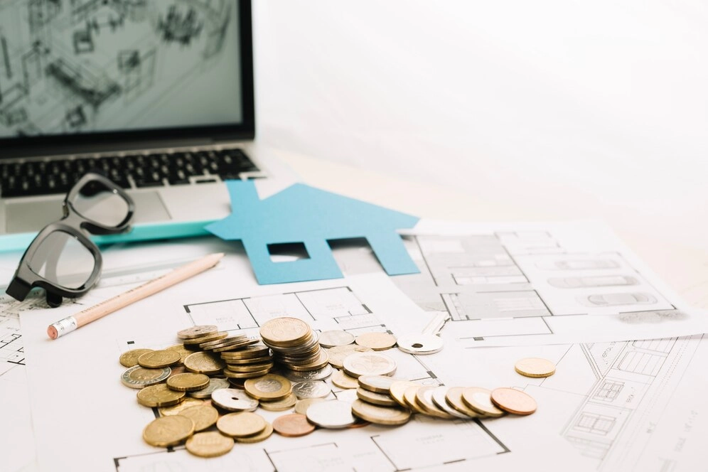 coins on top of paper with house cutout -real estate finance