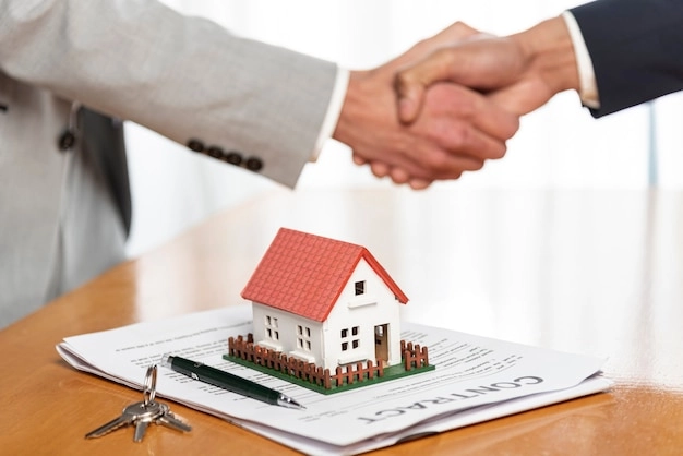 2 person handshake miniature house on paper -real estate promotion