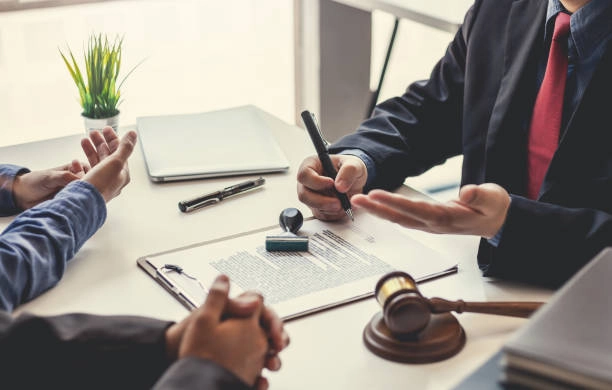 3 people conversing with paper on table and pen -real estate investment groups