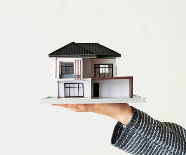 small miniature house on hand of person -real estate broker vs agent