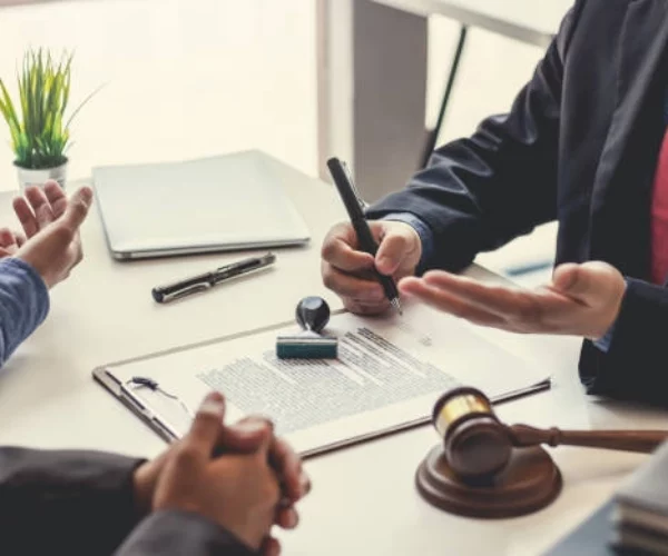 3 people conversing with paper on table and pen -real estate investment groups